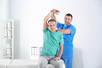 therapist stretching senior mans arm