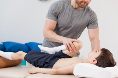 therapist doing knee stretching on little boy